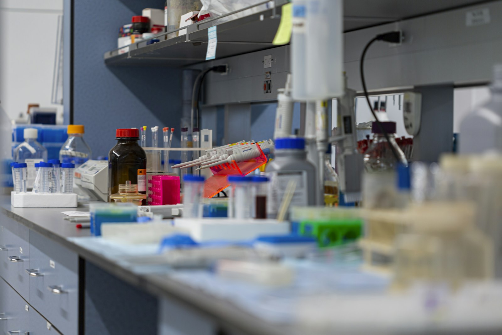A laboratory bench lined with reagent bottles and sample racks